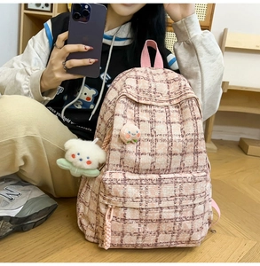 Detail of pink plaid corduroy backpack featuring a plush bear charm and peach patch
