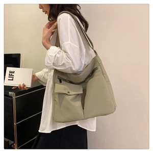 Dettaglio della grande borsa a tracolla in nylon verde salvia con multitasche e cinturino