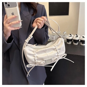 Détail d'un sac à main blanc plissé en cuir PU avec des nœuds décoratifs sur un mannequin