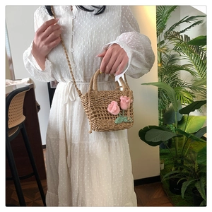Close-up of handmade straw woven bag featuring exquisite pink crochet tulip flowers