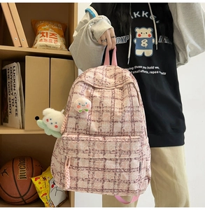 Detailed close-up of pink checkered corduroy backpack with bear and flower charms
