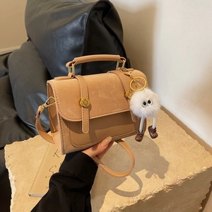 Khaki faux leather crossbody bag with metal buckle detail and plush charm decoration