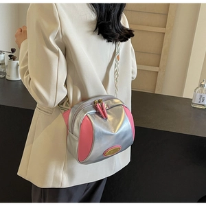 Umhängetasche aus silbernem und rosa Kunstleder mit gewebtem Gurt an einem Modell
