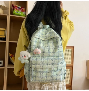 Detail view of mint green corduroy plaid backpack with cute peach patch and bear keychain