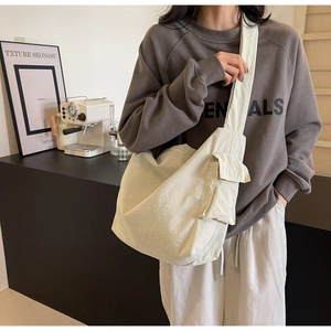 Detail view of a creamy white canvas crossbody bag showing side pocket and durable fabric