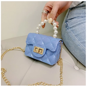 Détail du mini sac gelée bleu clair avec poignée en perles et texture matelassée en main
