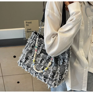 Detail der Tweed-Einkaufstasche mit Fransen, buntem Perlenanhänger und Silberkettenriemen
