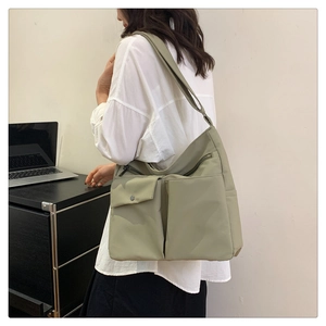 Dettaglio della borsa a tracolla in nylon verde chiaro con design multi-tasche in ufficio