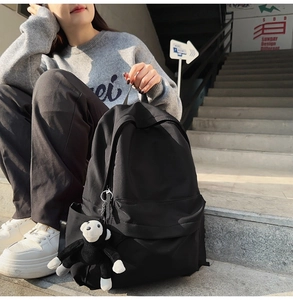Black nylon fashion backpack with front zip pocket and cute monkey plush keychain detail