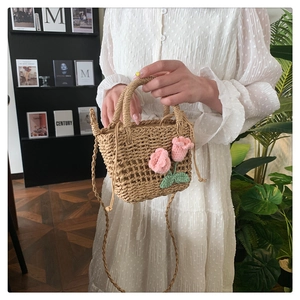 Detail of hand-woven straw bag featuring delicate pink crochet tulips and round handles