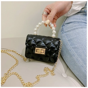 Détail d'un sac jelly noir matelassé avec poignée en perles et chaîne dorée