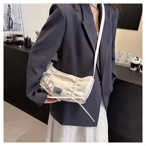 Sac bandoulière plissé crème chic avec détail nœud et décor argenté sur modèle