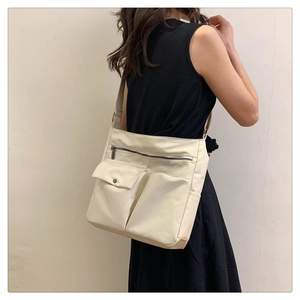 Modella che indossa una borsa a tracolla in nylon crema con tasche multiple e cinturino