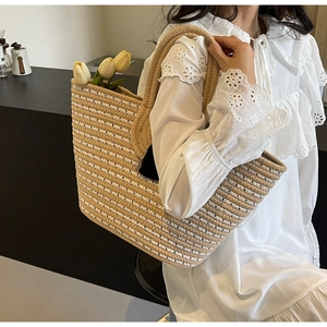 Close-up of woven straw tote bag with black and beige stripes and thick handles