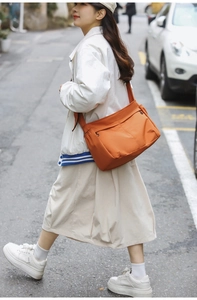 Vibrant orange nylon crossbody bag shown in a real-life streetwear commute fashion setting