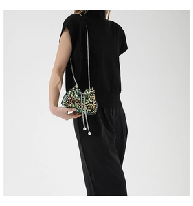 Detail of sequin bucket bag with pearl drawstring on a silver chain strap with model