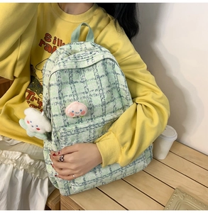 Close-up of green checkered corduroy backpack with peach patch and plush cloud charm
