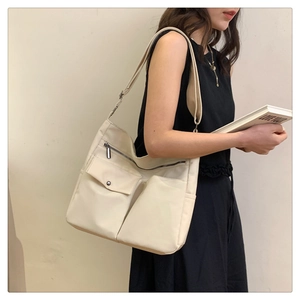 Dettaglio della borsa tote in nylon bianco sporco con tasche anteriori e tracolla sul modello