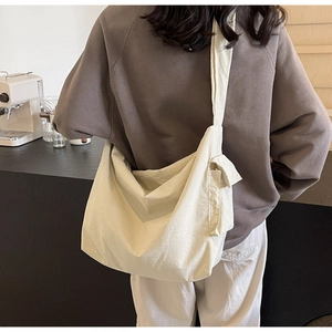 Close-up of cream canvas crossbody bag with wide shoulder strap and side flap pocket