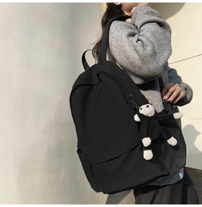 Detail of fashion black nylon backpack featuring a cute black and white monkey plush charm