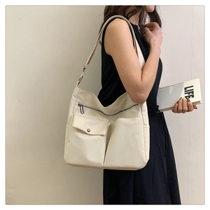 Modella che indossa una borsa a tracolla oxford crema con design a più tasche