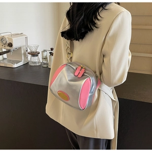 Detail der silber-pinken Umhängetasche mit Metallic-Effekt und breitem Mustergurt
