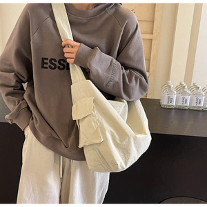 Detail view of large beige canvas crossbody bag showing spacious texture and wide strap