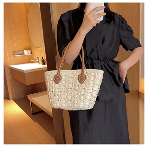 Detailed view of beige woven handbag featuring premium brown leather handles and mesh texture