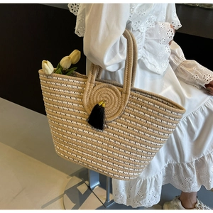 Close-up of woven straw tote bag with black tassel and thickened circular handles