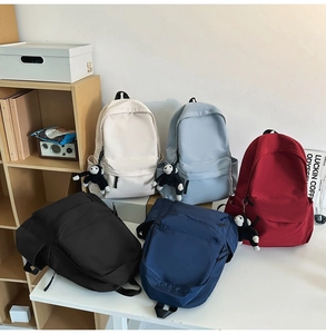 Group of minimalist nylon backpacks in multiple colors with plush charms in home setting