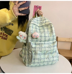 Detail view of light green corduroy backpack with cute peach brooch and bear charm