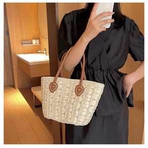 Detailed view of handmade hollow weave texture on beige tote with brown leather handles