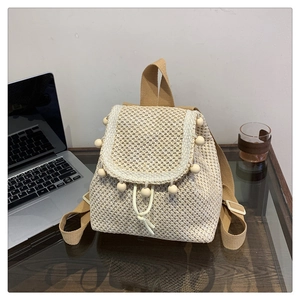 Fashionable woven straw backpack with drawstring closure and wooden bead accents for spring