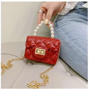 Détail d'un mini sac matelassé rouge avec poignée en perles et chaîne dorée chic
