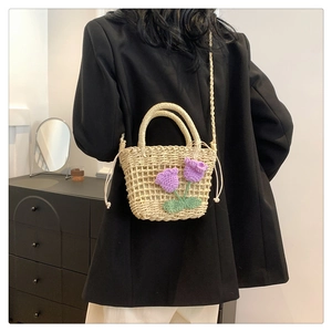Detail of hand-woven straw crossbody bag with 3D purple knit flowers and drawstring closure