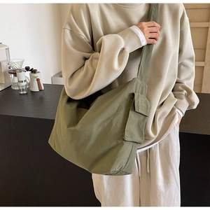 Detail of olive green nylon crossbody bag with front pocket shown on a model