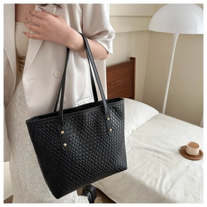 Détail du sac cabas tressé noir avec rivets métalliques dorés sur cuir synthétique PU