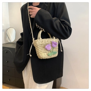 Detail of a mini straw bucket bag with hand-crocheted purple tulip floral decoration