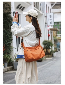 Detail view of durable orange nylon crossbody bag with multi-pocket design for women