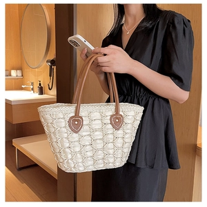 Detailed honeycomb woven texture of beige straw handbag with brown leather handles