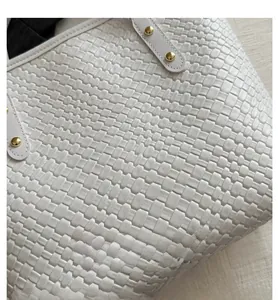 Gros plan sur la texture tressée du cuir PU blanc et les rivets dorés du sac à main