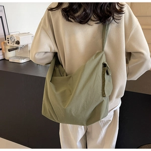 Olive green nylon crossbody bag showing spacious capacity and utility side flap pocket