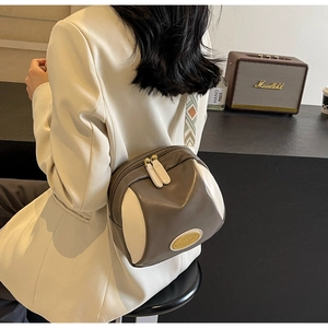 Detailansicht der Doppelreißverschlüsse und Goldlogo auf der grau-cremefarbenen PU-Tasche