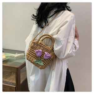 Detail of hand-woven straw crossbody bag featuring purple crochet tulip floral accents