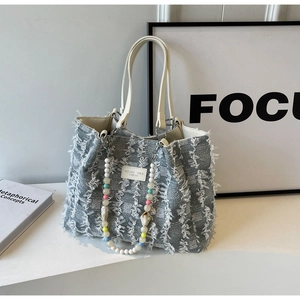 Schicke graue Web-Tote-Bag mit Fransendetails und bunter Perlenkette obenauf