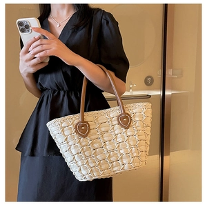 Detailed view of woven straw tote bag texture with brown leather handle accents