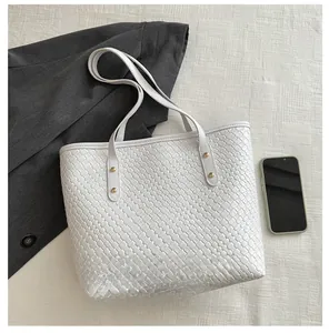 Détail du cabas tressé en cuir PU blanc avec rivets dorés et smartphone pour comparer la taille