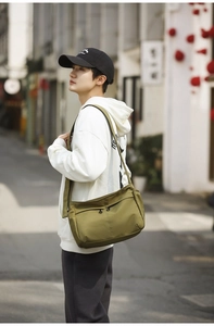 Outdoor lifestyle shot of army green nylon crossbody bag with dual zip pockets