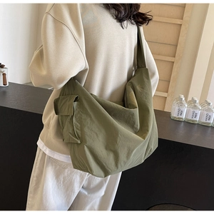 Macro view of olive green crossbody bag featuring functional side pocket and wide strap