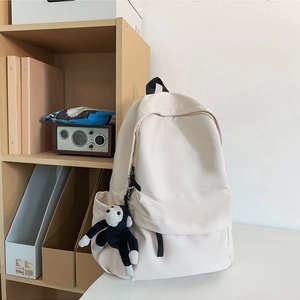 Minimalist beige nylon backpack with cute monkey pendant for fashion-conscious women